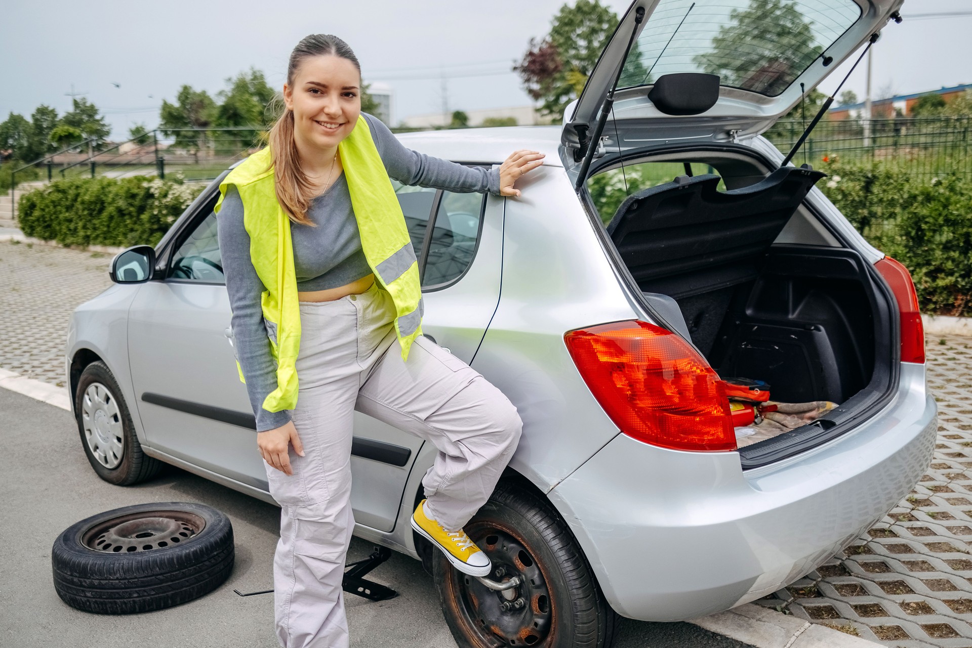 Portrait of woman changing flat tyre on her car